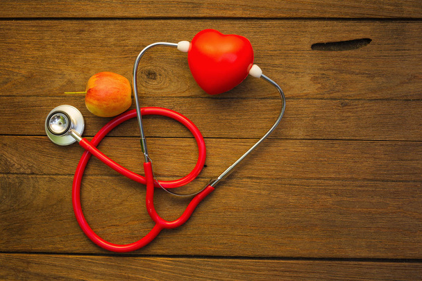 Стетоскоп з червоним серцем і яблуком на дерев'яному фоні
 - Фото, зображення