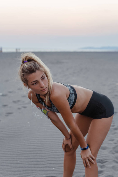 Beautiful Caucasian woman runner standing at beach. - Фото, зображення