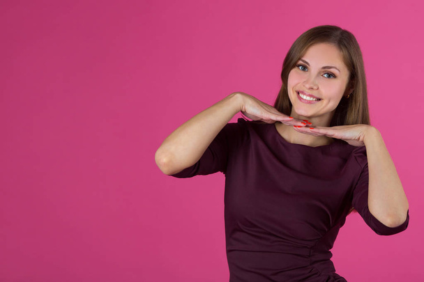 beautiful young girl with a smile on her face with flowing hair on a pink background - Foto, afbeelding