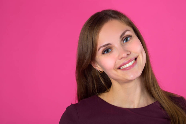 beautiful young girl with a smile on her face with flowing hair on a pink background - Foto, Imagen