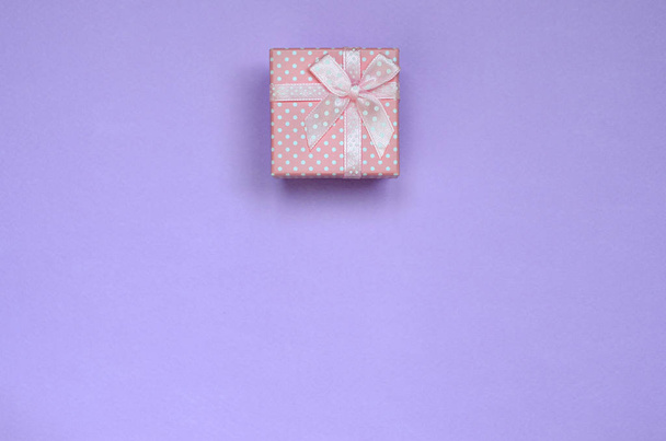 Small pink gift box lie on texture background of fashion pastel violet color paper in minimal concept. - Photo, Image