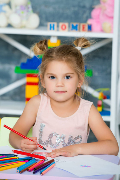 Pieni kaunis tyttö kiinnittää värikkäitä kyniä
 - Valokuva, kuva