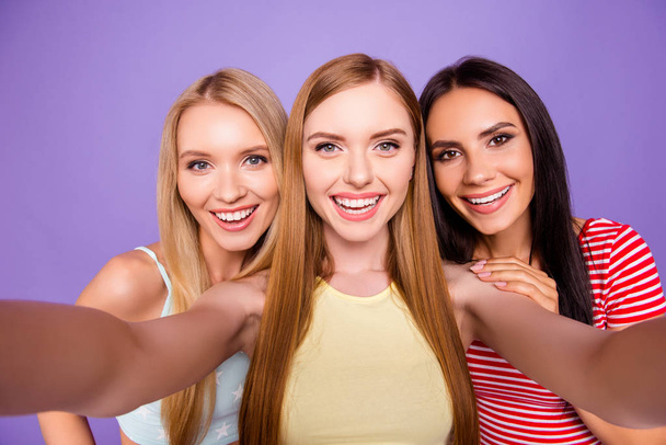 Self portrait of cheerful pretty girls shooting selfie on front camera having leisure isolated on vivid violet background. Vacation weekend rest relax holiday concept - Фото, изображение
