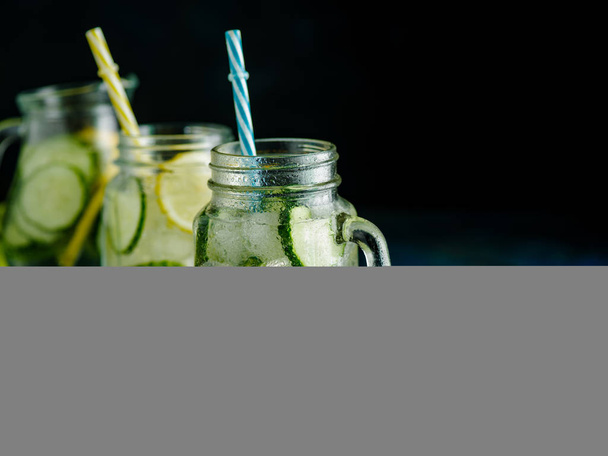 Friss nyári ital. Egészséges méregtelenítés szénsavas vizet citrommal és uborka befőttesüvegbe át sötét háttér előtt. Egészséges ételek fogalmát. Tisztítókúra. - Fotó, kép