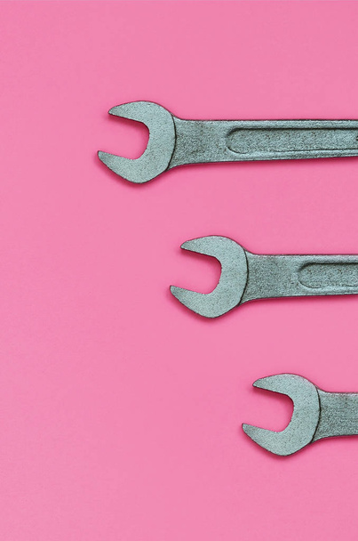 Three metallic spanners lie on texture background of fashion pastel pink color paper in minimal concept. - 写真・画像