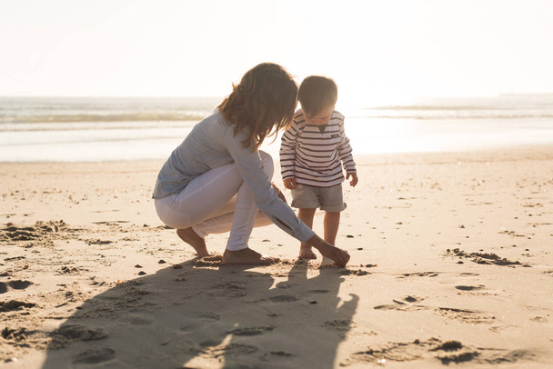 Jeune mère explorant la plage avec tout-petit
 - Photo, image