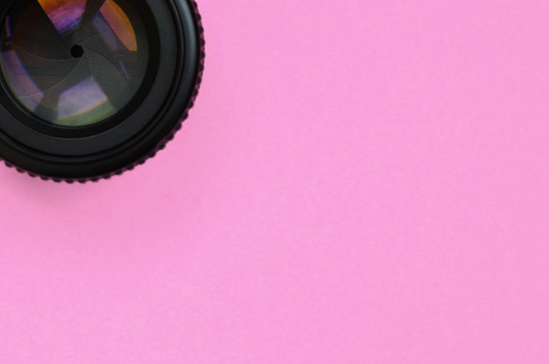 Camera lens with a closed aperture lie on texture background of fashion pastel pink color paper in minimal concept. - Photo, Image
