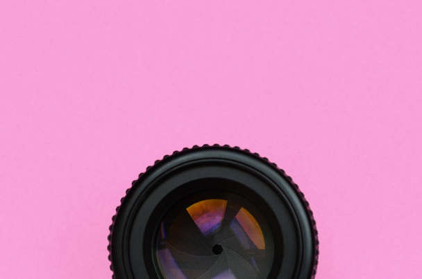 Об'єктив камери з закритою апертурою лежить на тлі текстури модного пастельного рожевого кольорового паперу в мінімальній концепції
. - Фото, зображення