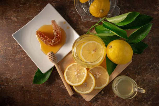 Zumo de limón con miel sobre mesa de madera, limones y hojas de salvia - Foto, Imagen