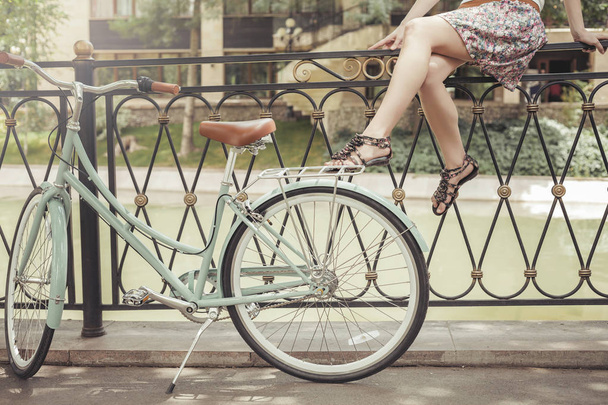 Young girl sitting on fence near vintage bike at park - Zdjęcie, obraz