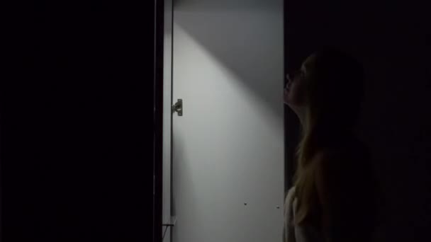 Young woman at night opens a wardrobe and choose the dress to on - Záběry, video
