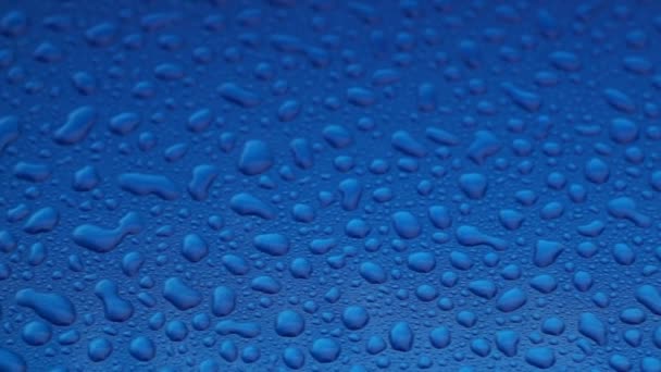Mavi pürüzsüz bir yüzey üzerinde yağmur damlaları - Video, Çekim