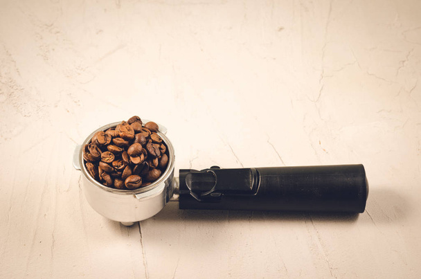 haltija täynnä kahvipapuja / suodatin haltija täynnä kahvipapuja betonitaustalla. Kopioi
 - Valokuva, kuva