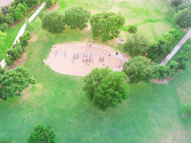 Aerial view of a big kid games playground at Harwin Park in Houston, Texas. An elevated view of slides and swings in the park surrounded by green trees. Children outdoor play and recreation concept. - Photo, Image
