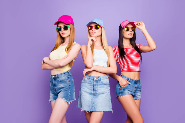 Portrait of dreamy proud girls in denim outifts standing in different poses isolated on bright violet background - Foto, imagen