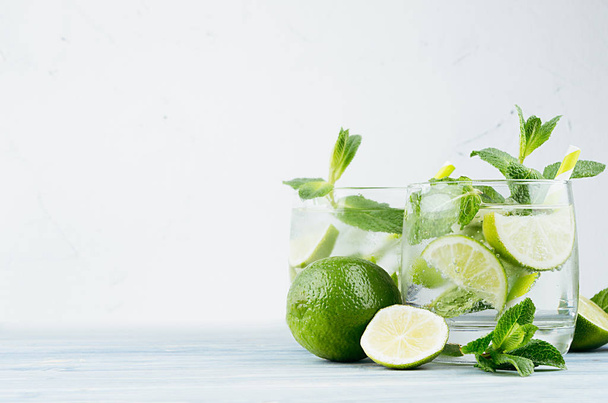 Cold detox summer mineral water with lime, mint, ice, straw on soft white background, copy space. - Zdjęcie, obraz