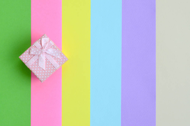 kleine rosa Geschenkbox liegen auf Textur Hintergrund der Mode pastellrosa, blau, grün, gelb, violett und beige Farben Papier in minimalem Konzept. abstraktes Trendmuster. - Foto, Bild
