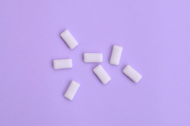 A few chewing gums lie on texture background of fashion pastel violet color paper in minimal concept. - Zdjęcie, obraz