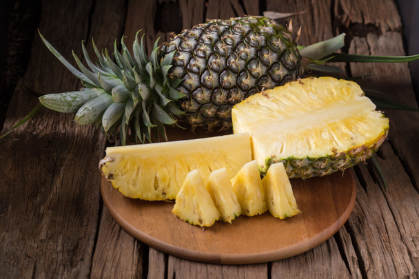 Pineapple slices and pineapple shelled on old wooden background - Fotó, kép