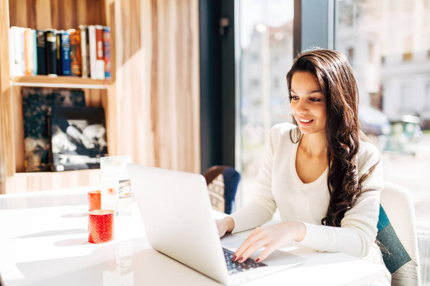 Beautiful young cute brunette using laptop in cafe - Foto, immagini