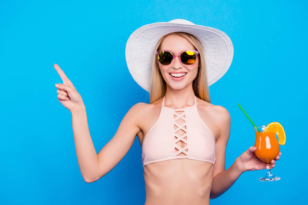 Advertisement weekend holiday recommend concept. Portrait of positive charming girl holding alcohol cocktail in hand gesturing product with forefinger isolated on vivid blue background - Φωτογραφία, εικόνα