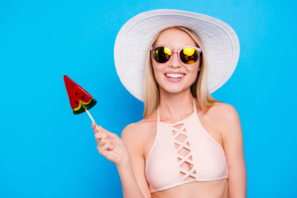 Portrait of toothy positive lady in eyewear holding peace of watermelon on stick looking at camera isolated on bright blue background. Healthy food nutrition lifestyle concept - Photo, Image