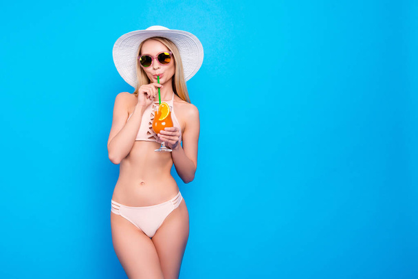 Portrait with copysapce empty place of stunning lady with perfect figure in pink two pieces swimsuit drinking sweet tasty cocktail isolated on bright blue background - Photo, Image
