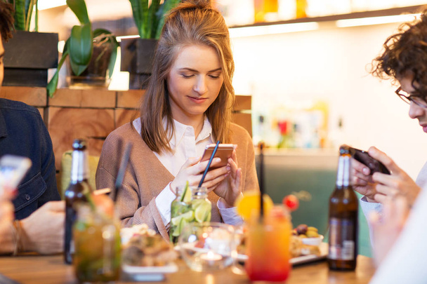 friends with smartphones eating at restaurant - Foto, Imagem