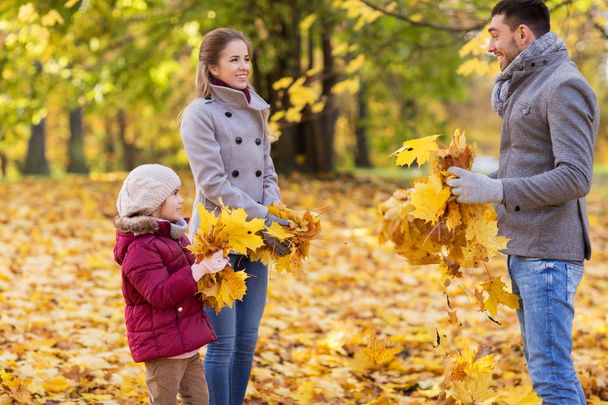happy family playing with autumn leaves at park - Fotó, kép