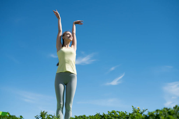 peaceful, slender girl doing yoga and meditating in the sun in the park, smiling - Φωτογραφία, εικόνα