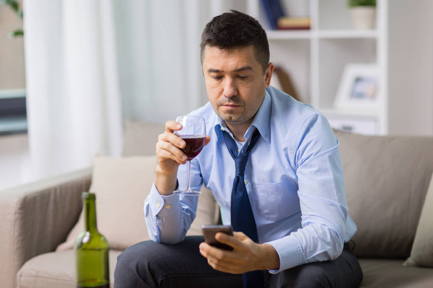 drunk man with alcohol and smartphone at home - Valokuva, kuva