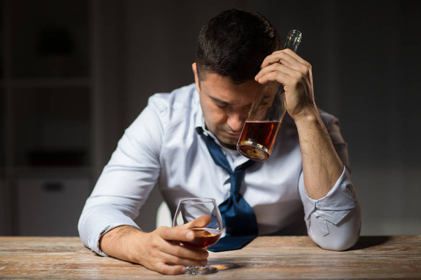 drunk man drinking alcohol at table at night - Zdjęcie, obraz