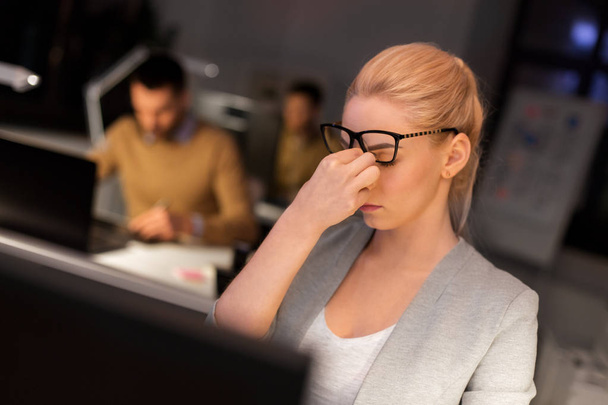 businesswoman rubbing tired eyes at night office - Foto, Bild