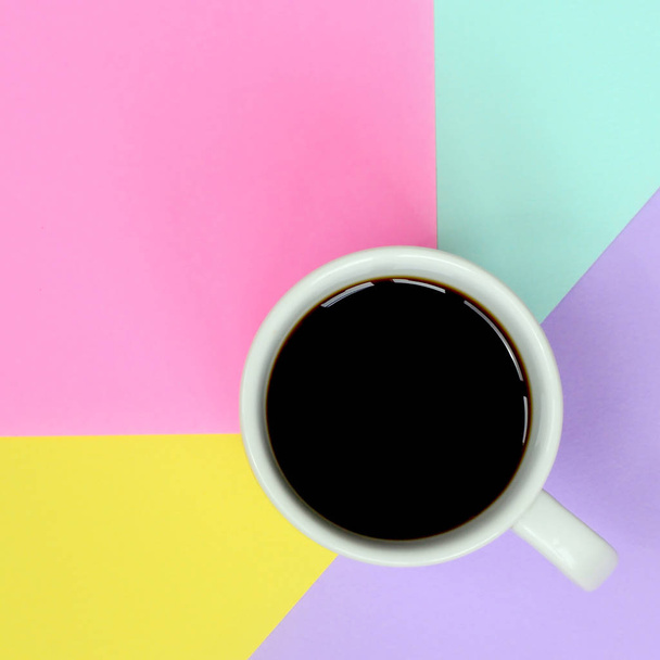 Pequeña taza de café blanco en el fondo de textura de la moda pastel azul, amarillo, violeta y rosa colores papel en concepto mínimo
. - Foto, Imagen