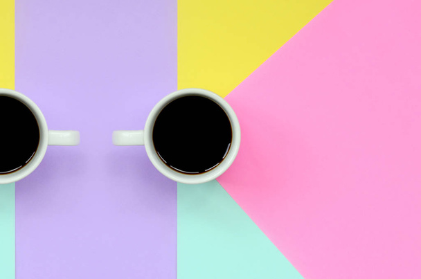 Pequeña taza de café blanco en el fondo de textura de la moda pastel azul, amarillo, violeta y rosa colores papel en concepto mínimo
. - Foto, imagen