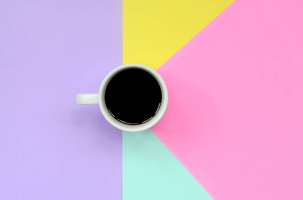 Kleine witte koffiekopje op textuur achtergrond mode pastel blauw, geel, violette en roze kleuren papier in minimale concept. - Foto, afbeelding