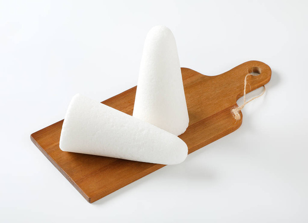 δύο άσπρα ψωμιά της ζάχαρης ή κώνους στο ξύλινο κοπή του σκάφους - Φωτογραφία, εικόνα