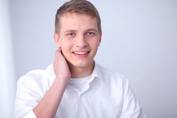 Portrait of young man smiling sitting on gray background. Portrait of young man - Valokuva, kuva