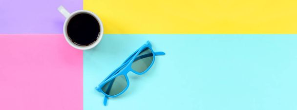 小さな白いコーヒー カップと青いサングラスのテクスチャ背景の最小限の概念でパステル調の青や黄色、紫、ピンク色の紙をファッションします。. - 写真・画像