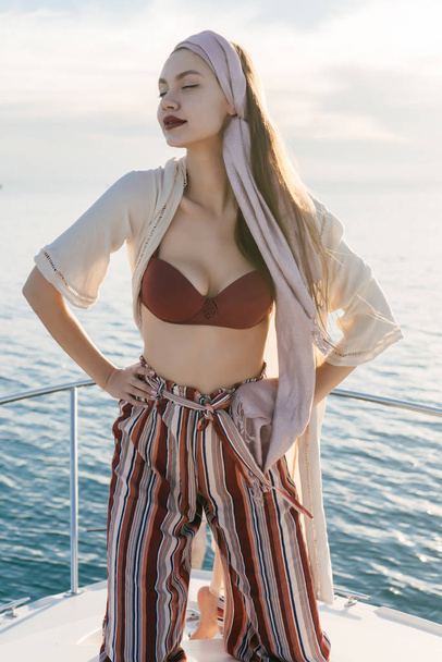 attractive stylish girl in summer clothes posing on her yacht, enjoying vacation and sea air - 写真・画像