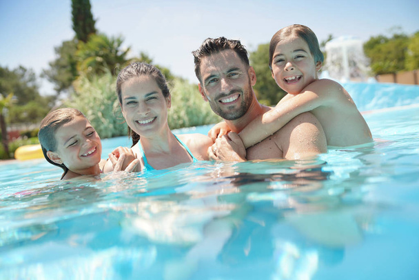 Retrato de familia feliz en la piscina en verano
  - Foto, imagen