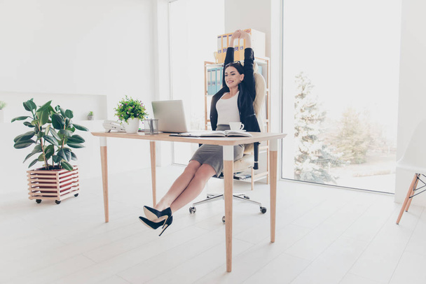 Full length size portrait of sexy trendy lawyer watching film movie video making stretching with raised hands enjoying break sitting in modern white workstation - 写真・画像