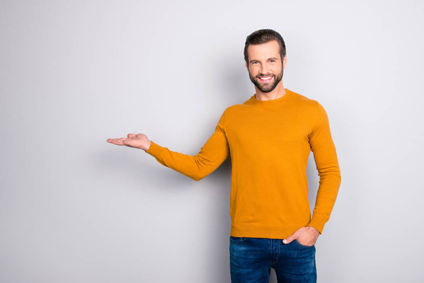 Look here! Attention! Portrait of handsome cheerful excited satisfied confident marketer wearing casual outfit keeping hand in pocket demonstrating empty place on his palm isolated on gray background - Фото, зображення