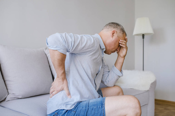 Closeup of mature man suffering from pain back while sitting on bed at home, People with body-muscles problem, Healthcare And Medicine concept - Foto, imagen