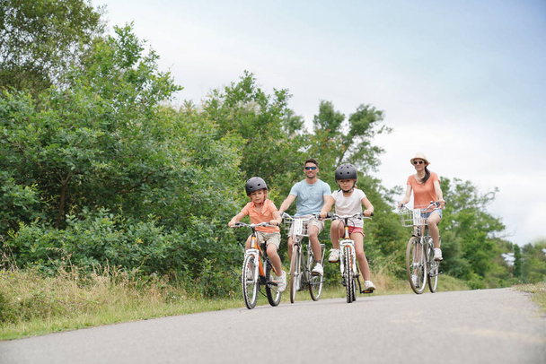 Kids with parents riding bikes in countryside - Photo, Image