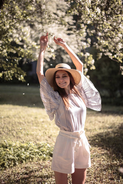 Pretty young woman in a summer garden, casual romantic style with hat - Fotografie, Obrázek