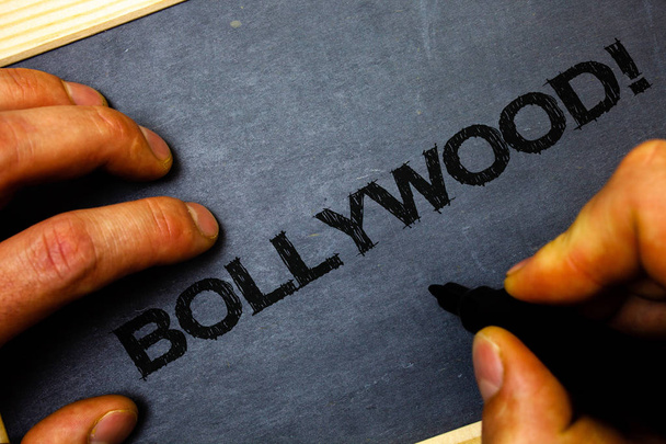 Texto de escritura de palabras Bollywood Motivational Call. Concepto de negocio para Hollywood Movie Entertainment Cinema Man hold holding negro marcadores cuaderno madera fondo de madera
 - Foto, imagen