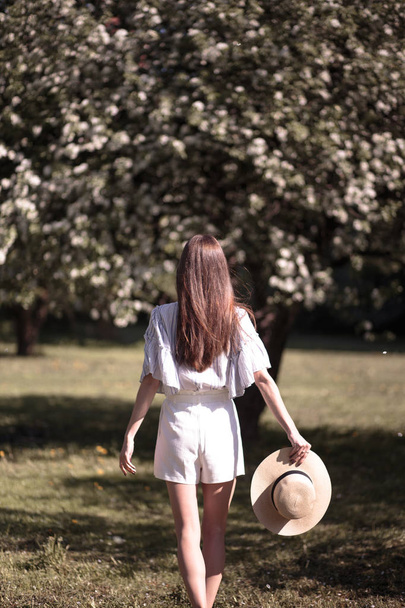 Pretty young woman in a summer garden, casual romantic style with hat - Foto, Bild
