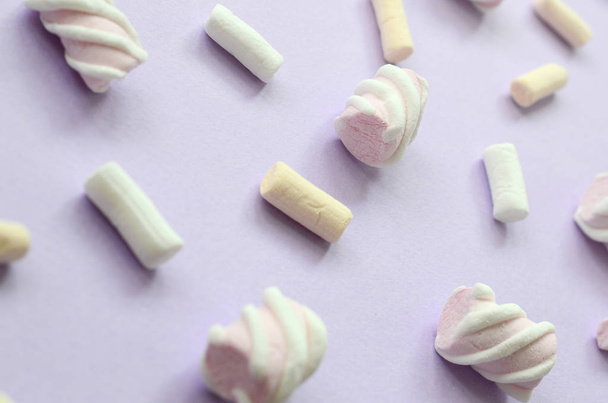 Marshmallow colorido colocado no fundo de papel violeta. padrão texturizado criativo pastel. Perspectiva macro shot
. - Foto, Imagem