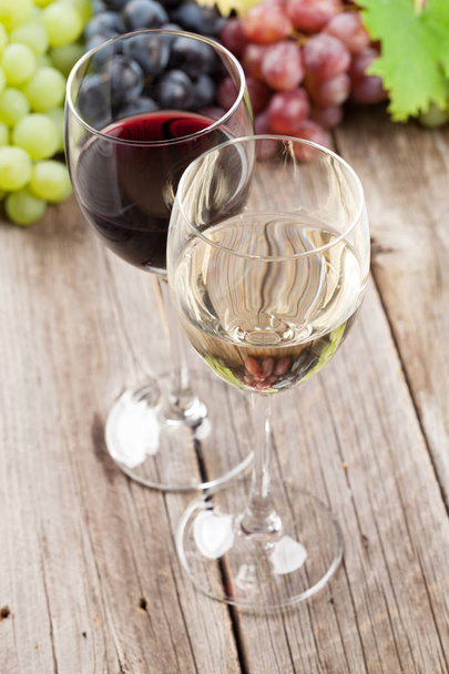 Ποτήρια κρασί και σταφύλια σε ξύλινο τραπέζι - Φωτογραφία, εικόνα